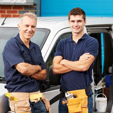 Two tradies standing with their arms crossed in front of a white van.