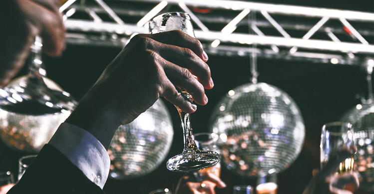 People celebrating with glasses of champagne surrounded by disco balls.