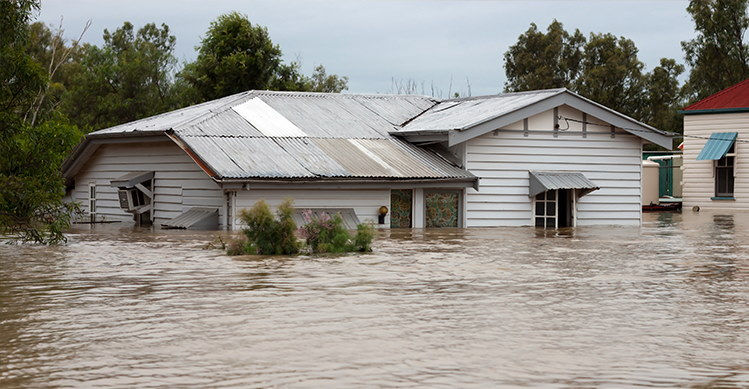 The yard of a house completely flooded and the house nearly submerged in water.