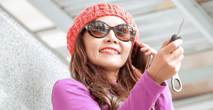 Girl with brown hair holding a car key whilst on the phone.