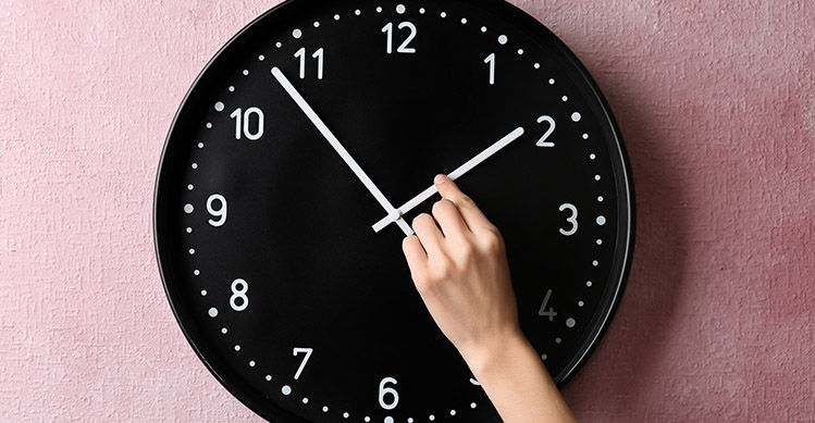 Person changing the hands of a black and white clock.