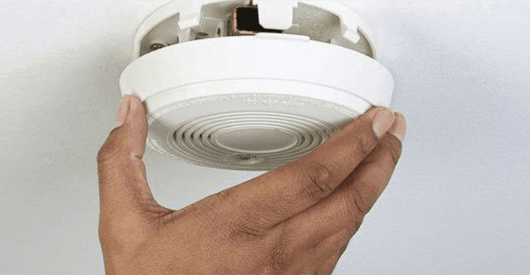 Person opening up a smoke alarm to change battery.