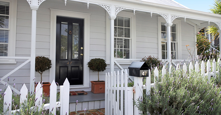 The front of a house where the gate of the fence has been left opened.