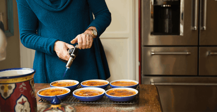 Person torching the sugar on top of crème brulee.